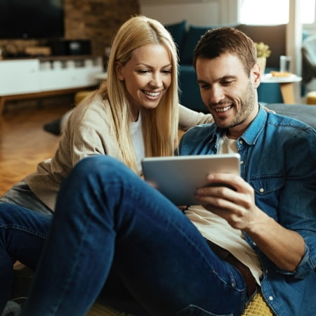 Par kigger på privatlån på en tablet i deres stue