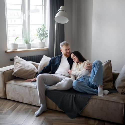 Ungt par sidder i en sofa i en stue